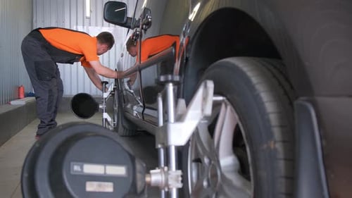 Two Men are Repairing a Vehicle Focusing on Tires and Wheels in a Garage