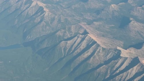 High altitude aerial view of rugged mountain terrain with visible ridgelines and shadows