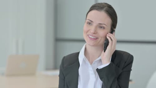 Smiling Business Woman Talking on Cell Phone in Office