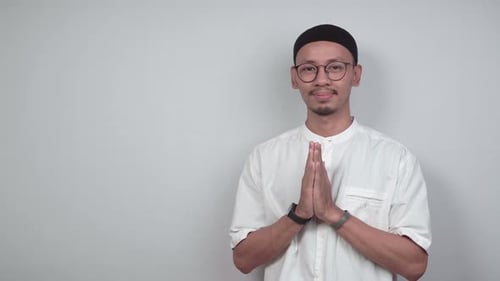 Muslim Man Offering Greeting in Front of White Wall
