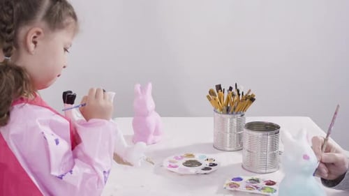 Little Girl Painting Paper Mache Figurines with Acrylic Paint for Her Homeschooling Art Project