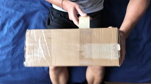 Man wraps a cardboard box with packing tape