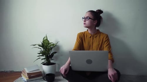 Woman with Laptop Sitting Cross-Legged on Rug Indoors