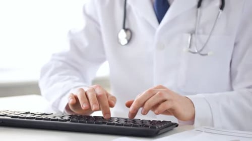 Nahaufnahme männlicher Arzthände, die auf der Tastatur tippen
