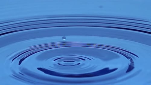 Water Drop Ripples in Blue Liquid
