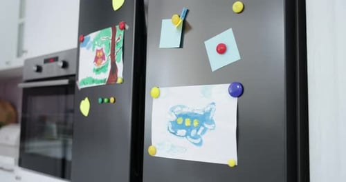 Refrigerator with child's drawings and magnets indoors, closeup