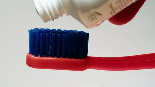 Blaue Zahnpasta, die auf einen Pinsel vor weißem Hintergrund aufgetragen wird. Morgendliche medizinische Zahnpasta