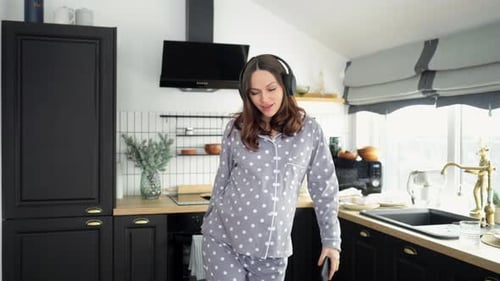 Woman Dancing in Kitchen with Headphones and Phone