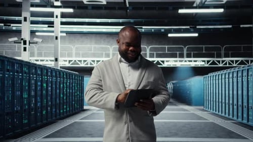 System Administrator Walking in Server Farm Deploying Infrastructure