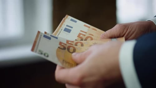 Empresario desconocido sosteniendo de cerca un paquete de billetes de euro en el interior. Manos de hombre