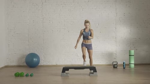 Young Woman Doing Step Aerobics in Gym