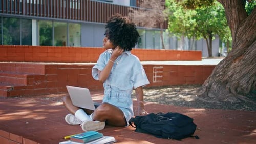 African Girl Taking Earphones Sitting Sunny Park with Laptop on Knees Close Up