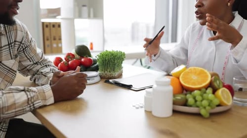 Nutritionist Making Notes at Desk with Medicine and Products