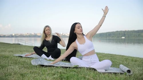 Beautiful Women Doing Yoga or Stretching on the Green Grass Near the Lake Sports Girls at Training