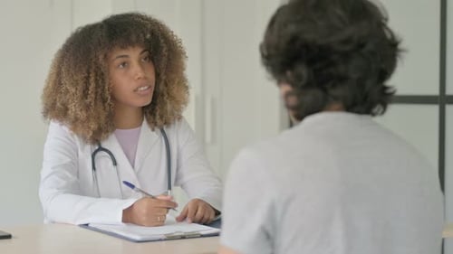 African Female Doctor Talking with Patient in Clinic