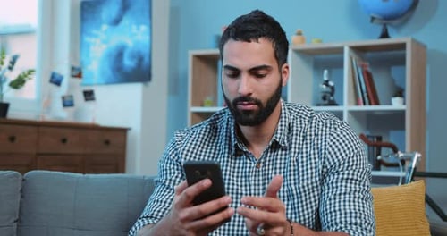 Close Up Attractive Young Man Typing Message on the Phone Smiling Feel Happy Sit on Sofa Home