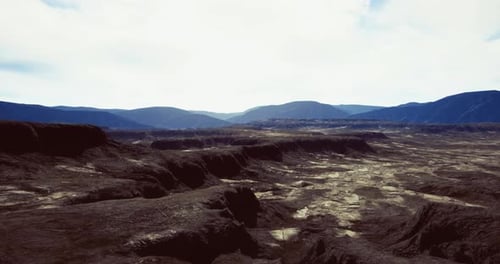 Slow Fly Over Desolate Rocky Landscape with Distant Mountains