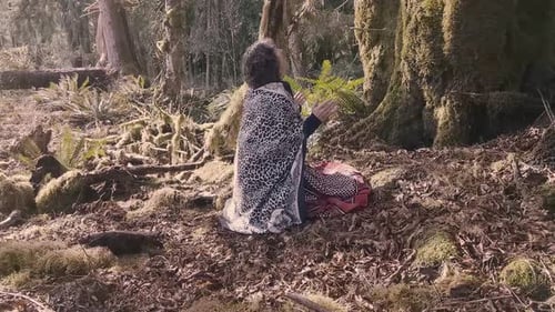Femme chamane agenouillée et honorant ses ancêtres pour l'abondance de la nature dans une forêt tropicale
