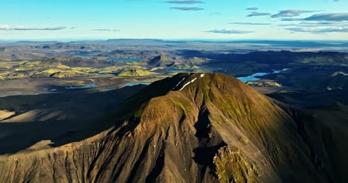 A dramatic trailer-style aerial over Iceland’s volcanic peak, revealing ripped crater walls, vast