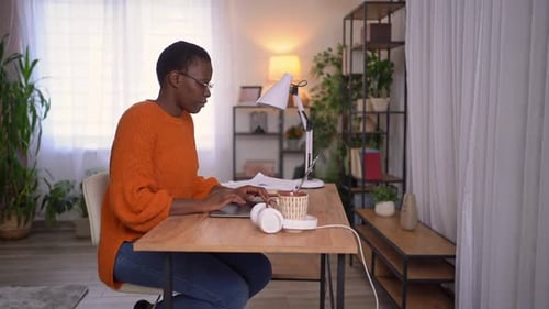 Young woman working from home office, she receives a phone call and continues her work on the laptop