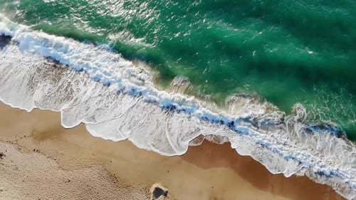 Stunning Aerial View of Emerald Waves Crashing on a Golden Beach