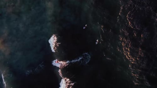 Aerial View of Surfers on the Ocean at Sunset