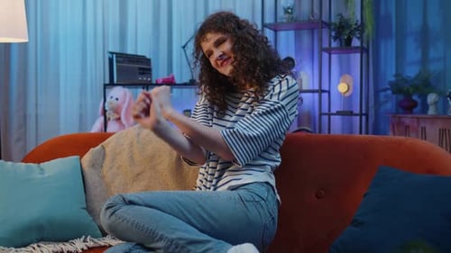 Happy Woman Gesturing on Orange Couch at Home