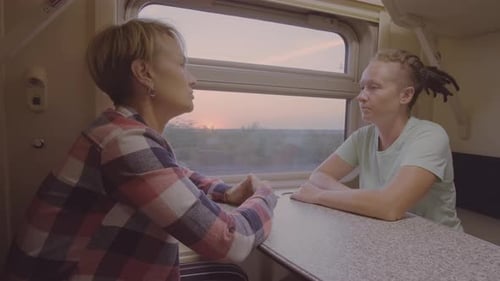 Deux femmes parlent alors qu'elles se trouvent dans le compartiment du train, assises près d'une fenêtre