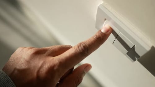 Finger Pressing Doorbell Button Inside Home
