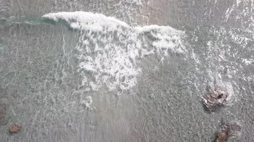 Scenic view of waves breaking on shore with umbrellas on sunny day