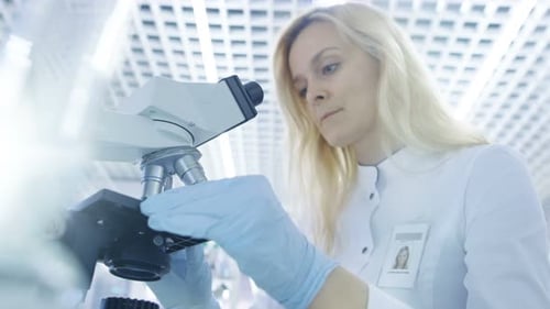 Low Angle Shot of Medical Research Scientists putting Slides in Place and Looking at Samples Under
