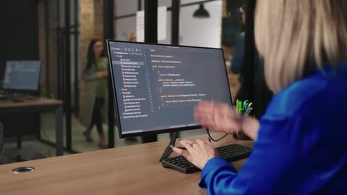 Gruppe weiblicher IT-Spezialistinnen, die gemeinsam Programmcode schreiben und über die Ansicht auf dem Computerbildschirm diskutieren