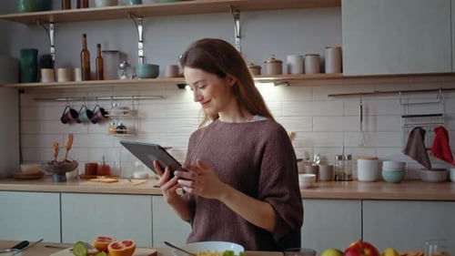 Happy Woman Eats Snacks and Scrolls Internet on Digital Tablet