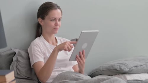 Woman Using Tablet in Bed at Home