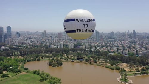 Aerial Shot Of Hot Air Balloon Descending Over Yarkon Park Against Sky In City