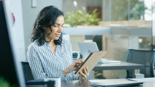 Woman Using Tablet Device at Desk in Modern Office