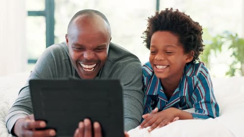 Father and Son Laughing at Tablet in Bedroom