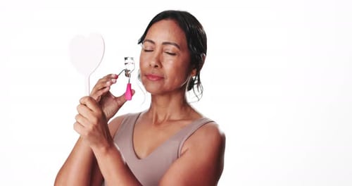Woman, mirror and eyelash curler in studio for makeup, beauty aesthetic and mascara preparation
