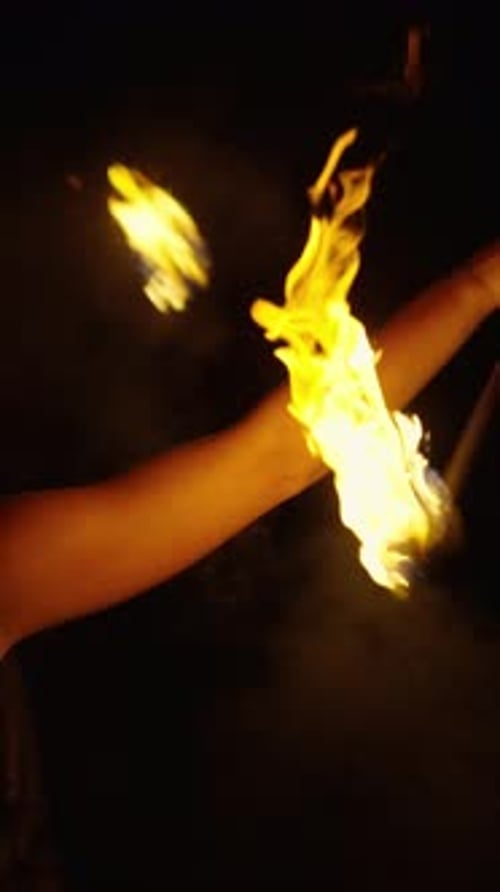 Lächelnder Feuerkünstler, der lodernde Flammen in der Dunkelheit wirbelt und Dramatisch Lichtspuren erzeugt und