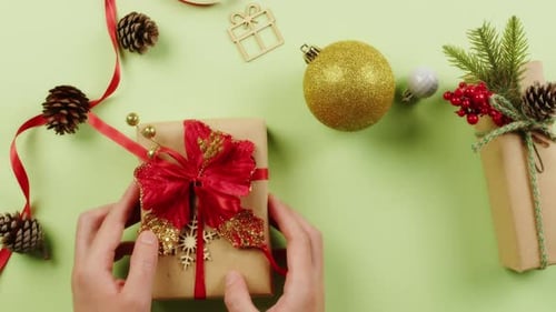 Girl's Hands Place a Gift for Christmas on the Green Table