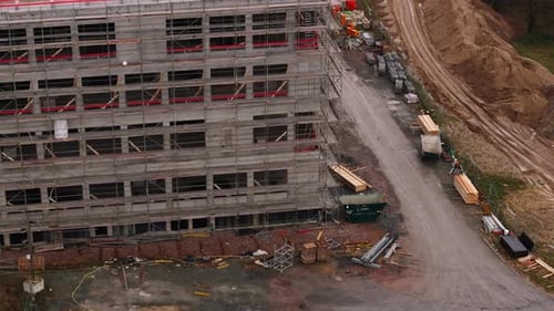 Luftaufnahmen eines mehrstöckigen Gebäudes aus Beton auf der Baustelle und des darauf gestapelten Materials