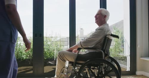 Senior Man in Wheelchair Holding Hands with Nurse