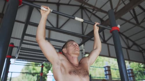 Man Doing Pullups on the Horizontal Bar on the Street