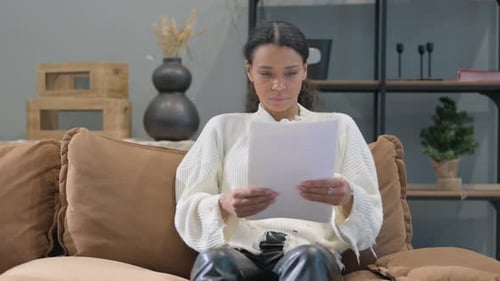 Woman Sitting Reading Papers on a Couch
