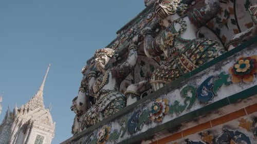 close-up of the ornate architectural details of Wat Arun, with intricate statues and colorful floral
