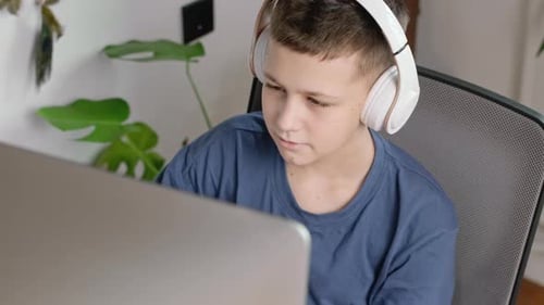 Teenager Using Laptop with Headphones at Home