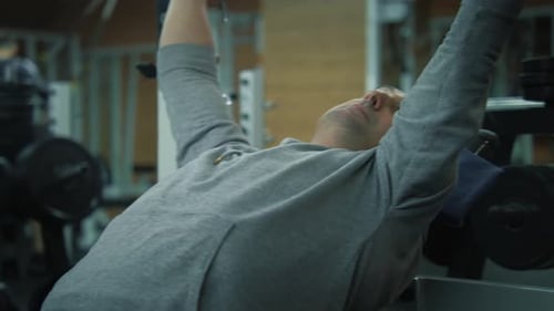 Athletic Active Man Exercises with Empty Barbell in Fitness Center