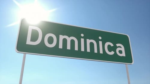 Green Highway Sign Saying Dominica in Tropical Sunlight