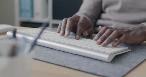 Hands Typing on a Keyboard at Desk