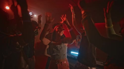 Energische Menge von Ravern, die im Club mit roter Neonbeleuchtung zu EDM tanzen